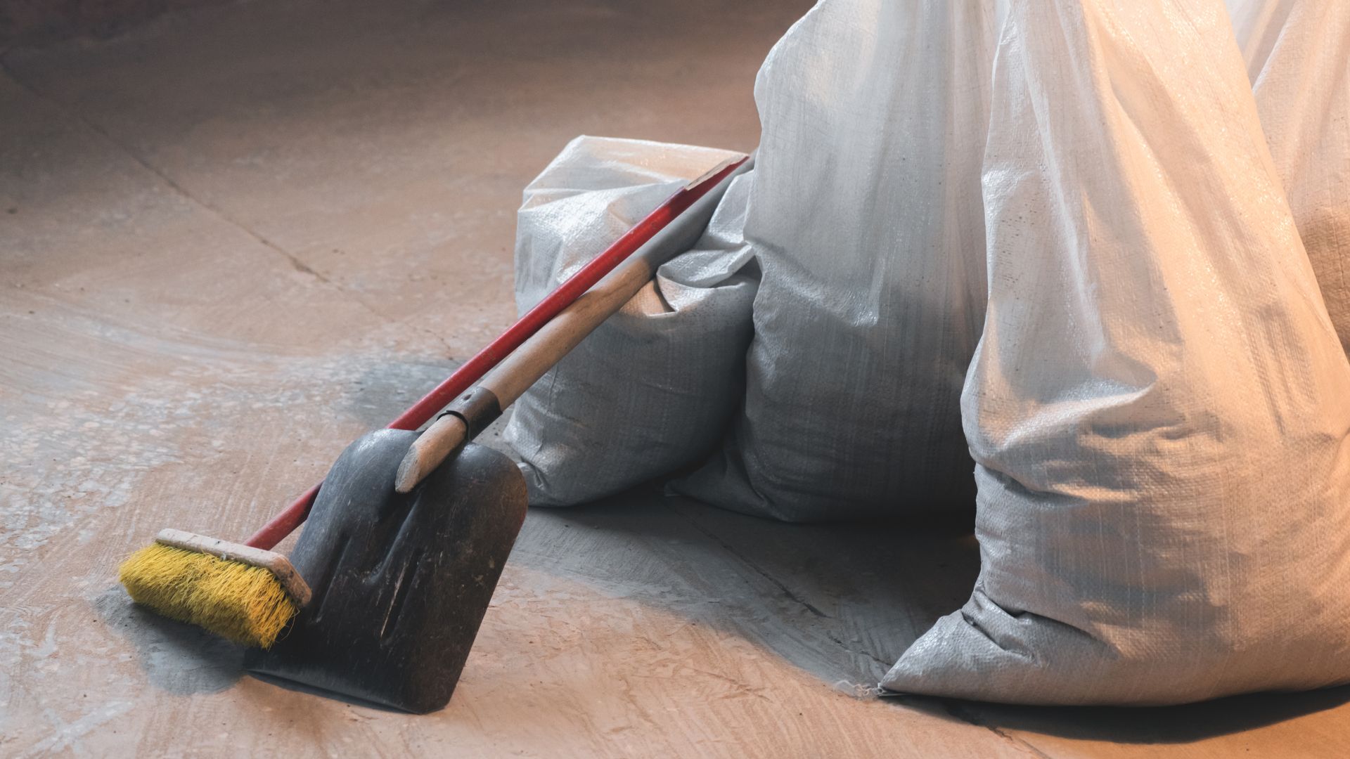 Dustpan, broom, and gray bags on wooden floor