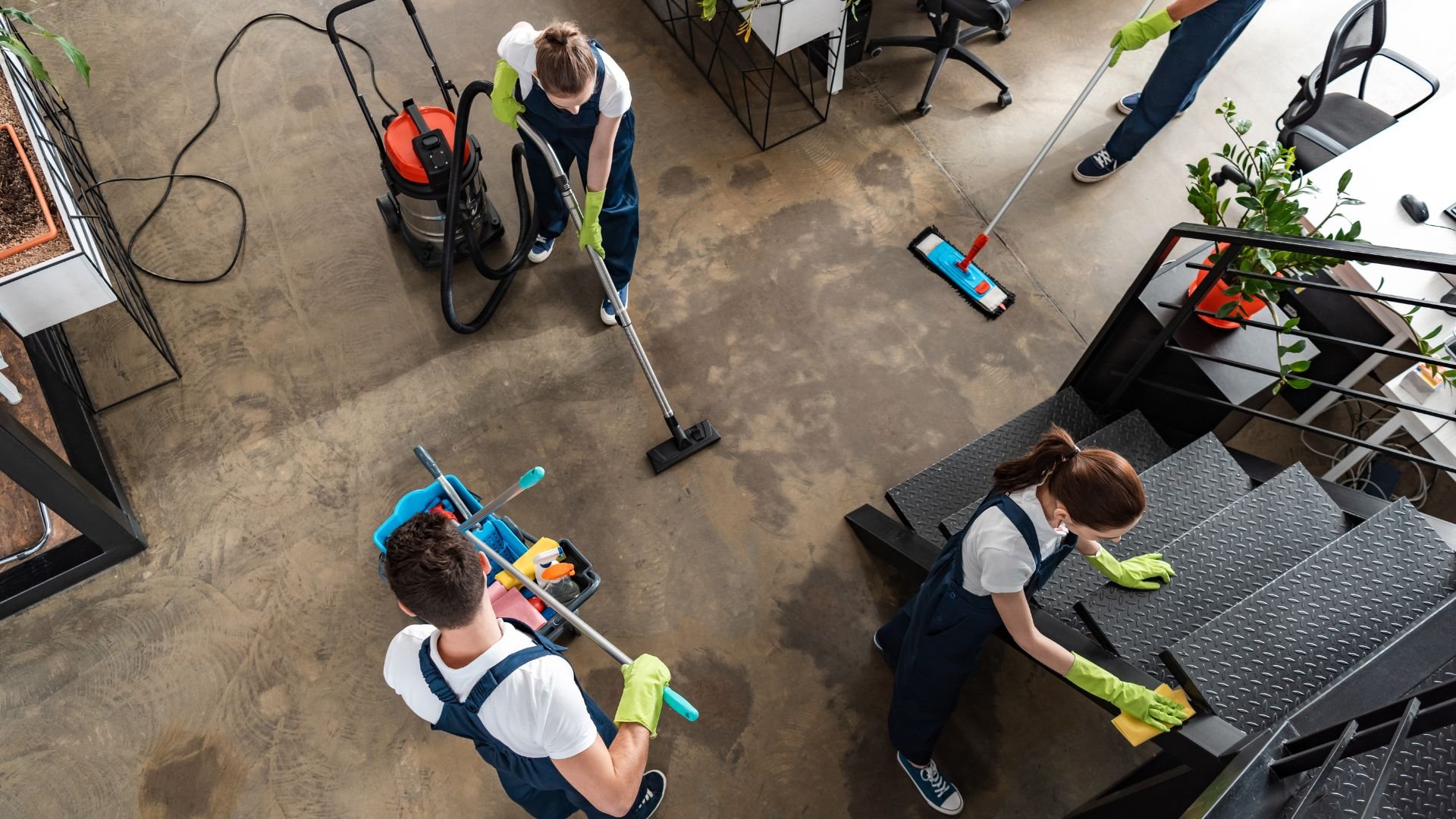 Cleaning team with vacuum and mop working together in an office space