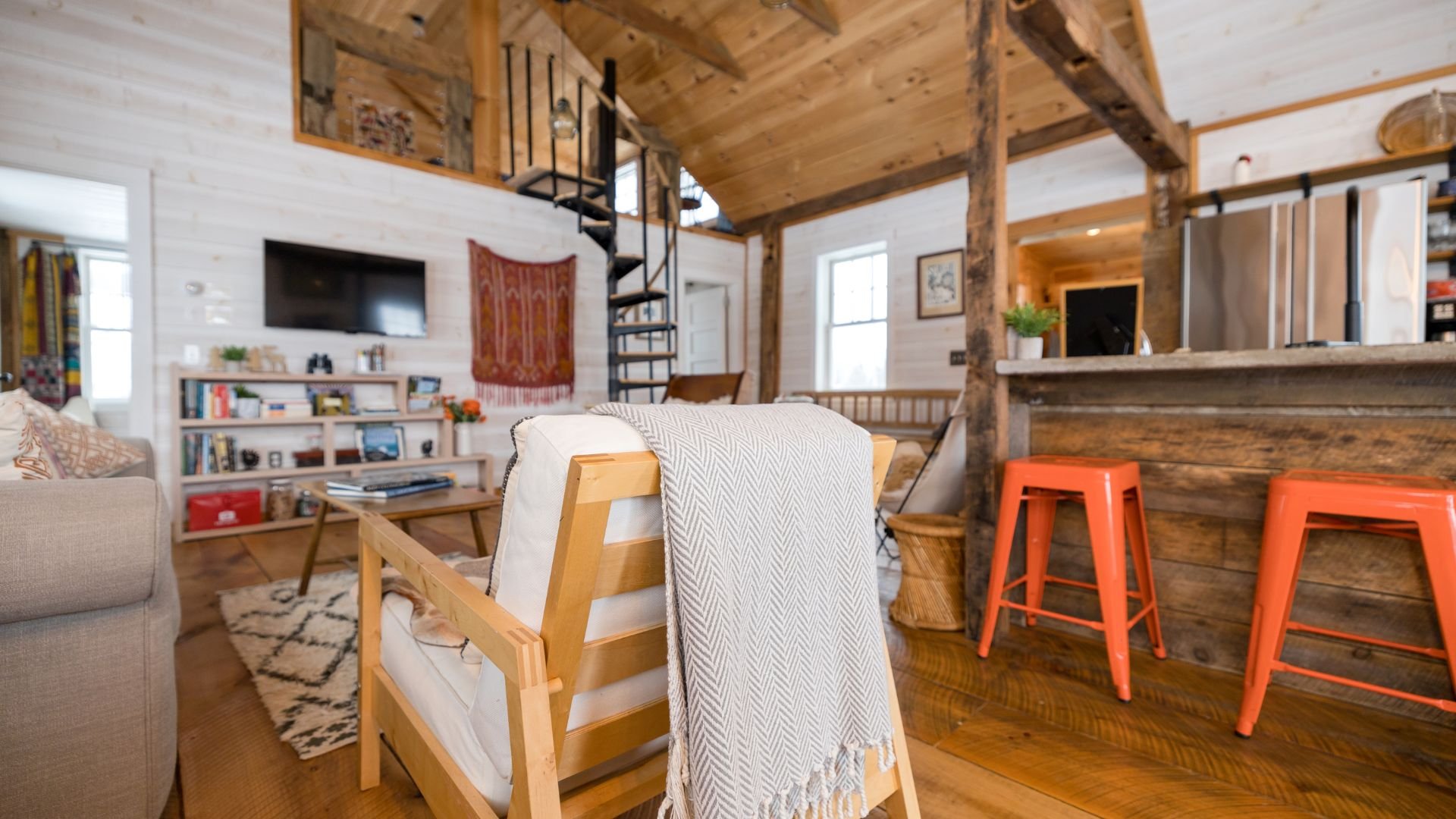 Rustic wooden cabin interior with orange stools and spiral staircase