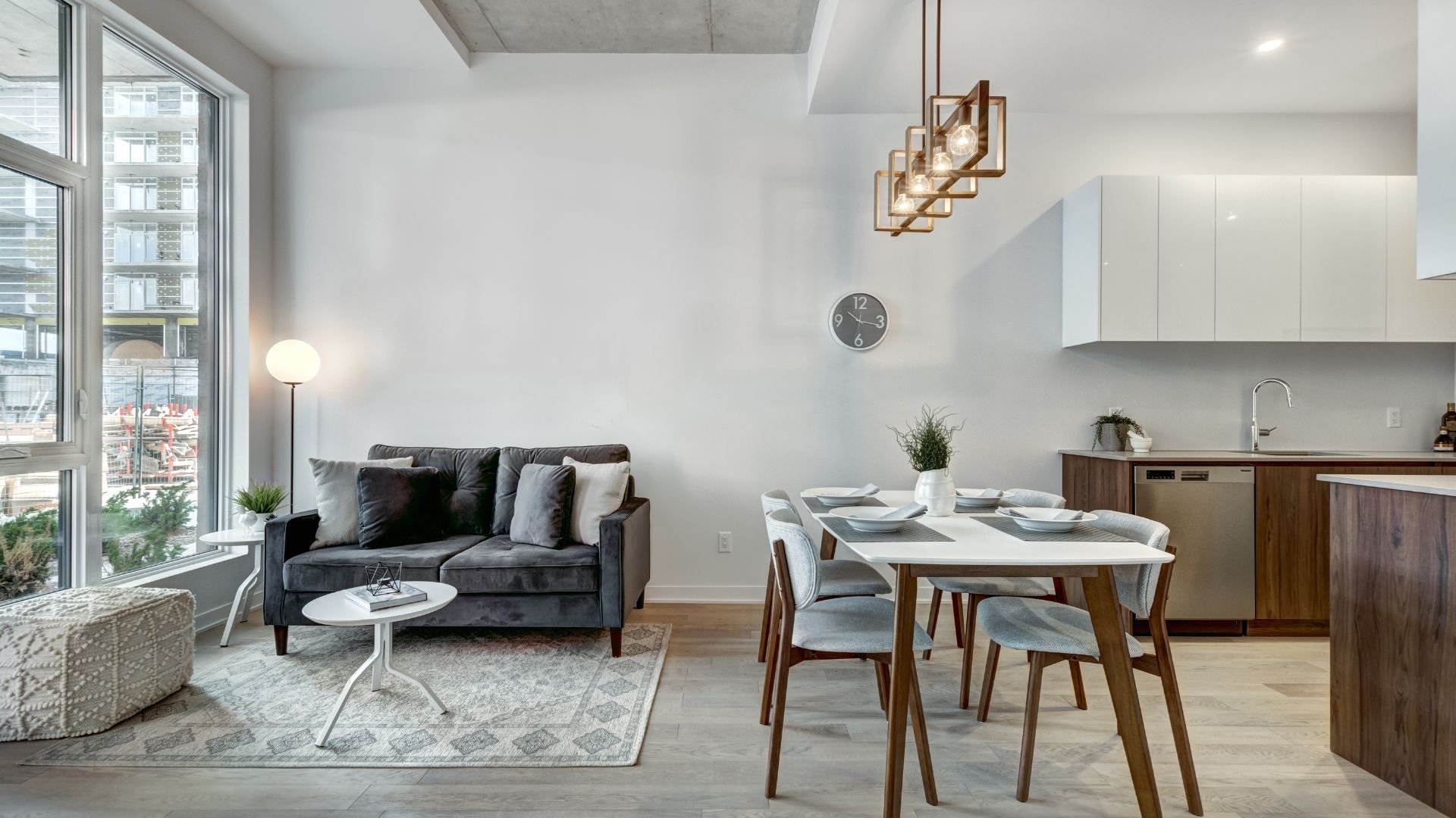 Modern apartment with grey sofa, dining table, and large windows